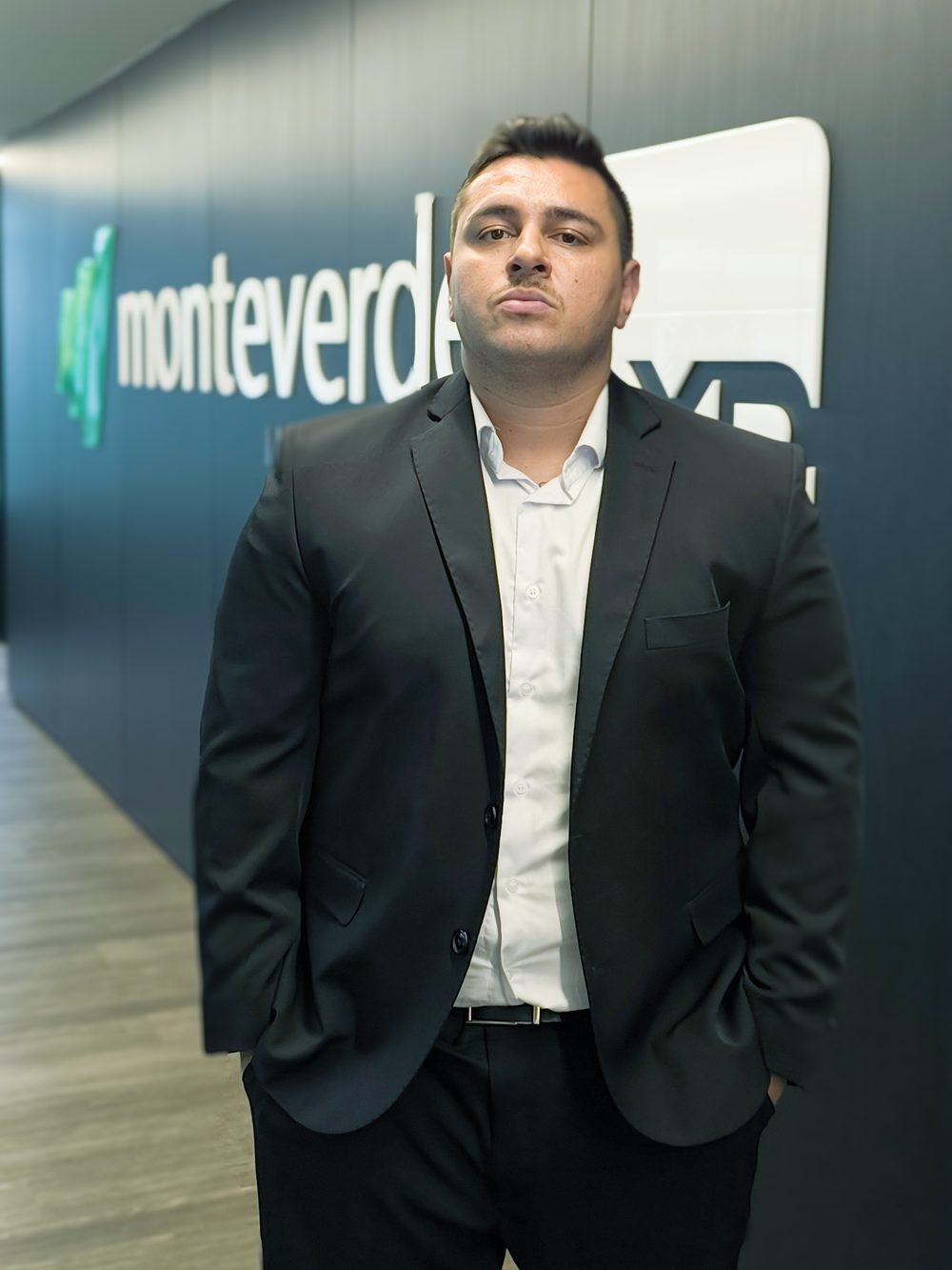 Vinicius Moreira no escritório, com a parede da XP Investimentos ao fundo